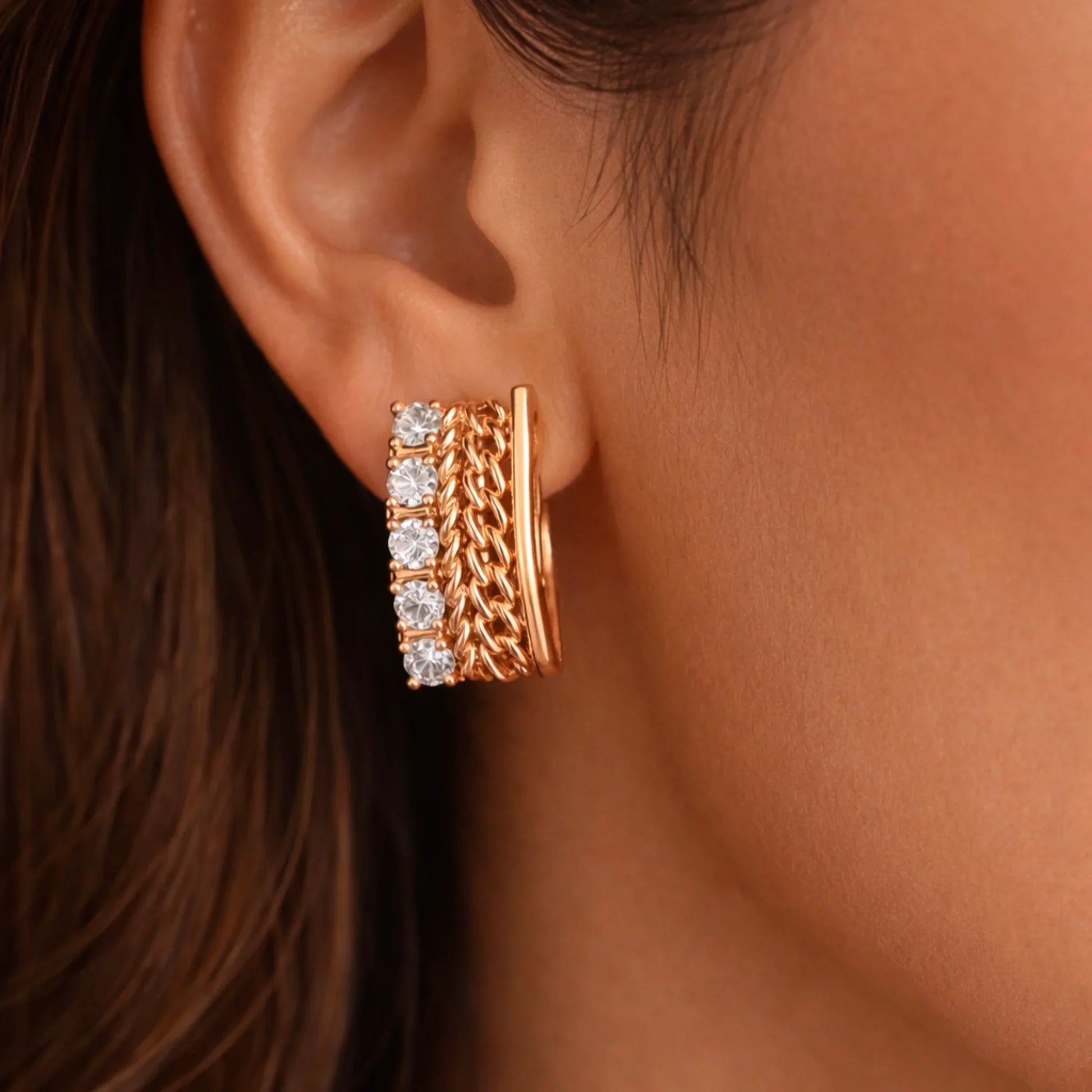 YUBIRAA gold huggie hoop earrings with chain detailing and diamonds worn on ear, close-up view