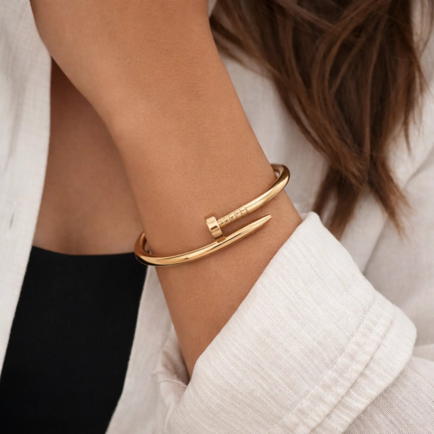 Gold bracelet on a wrist with a neutral background