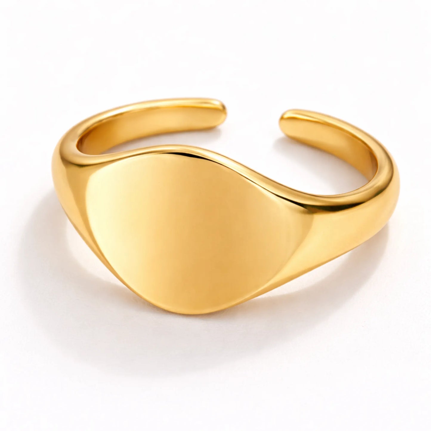 Gold polished signet ring with curved smooth face on white background