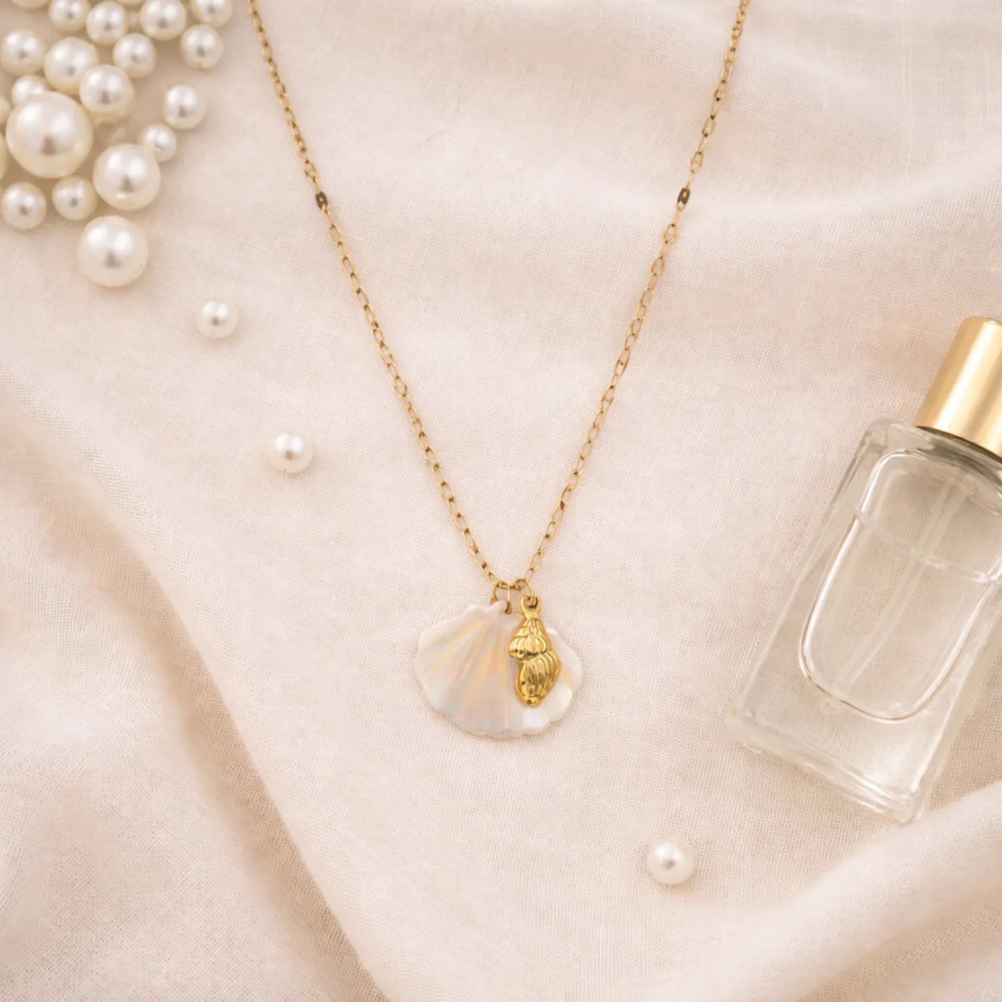 Mother of pearl shell pendant necklace styled in soft neutral flat lay with pearls and minimal lifestyle props