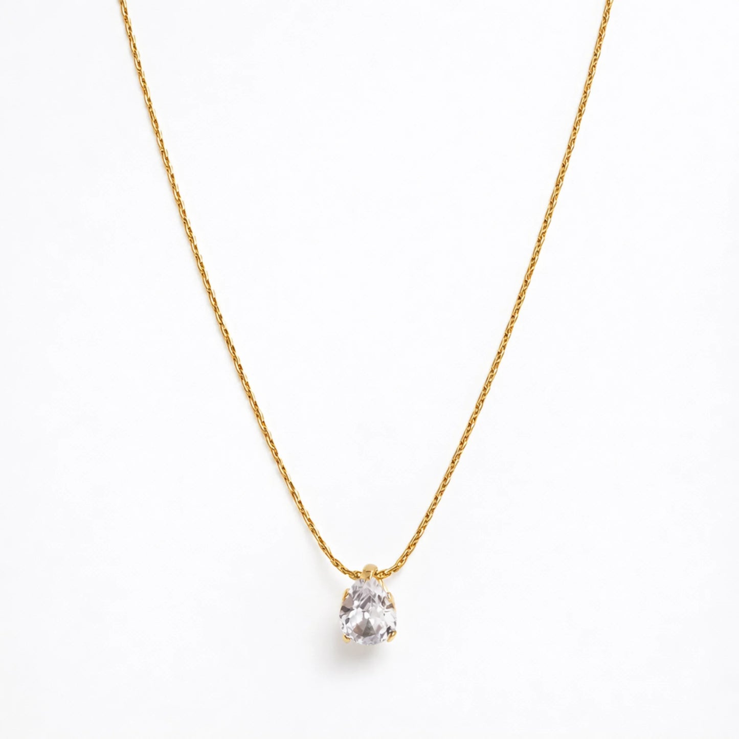 Gold necklace with a clear pendant tear drop on a white background