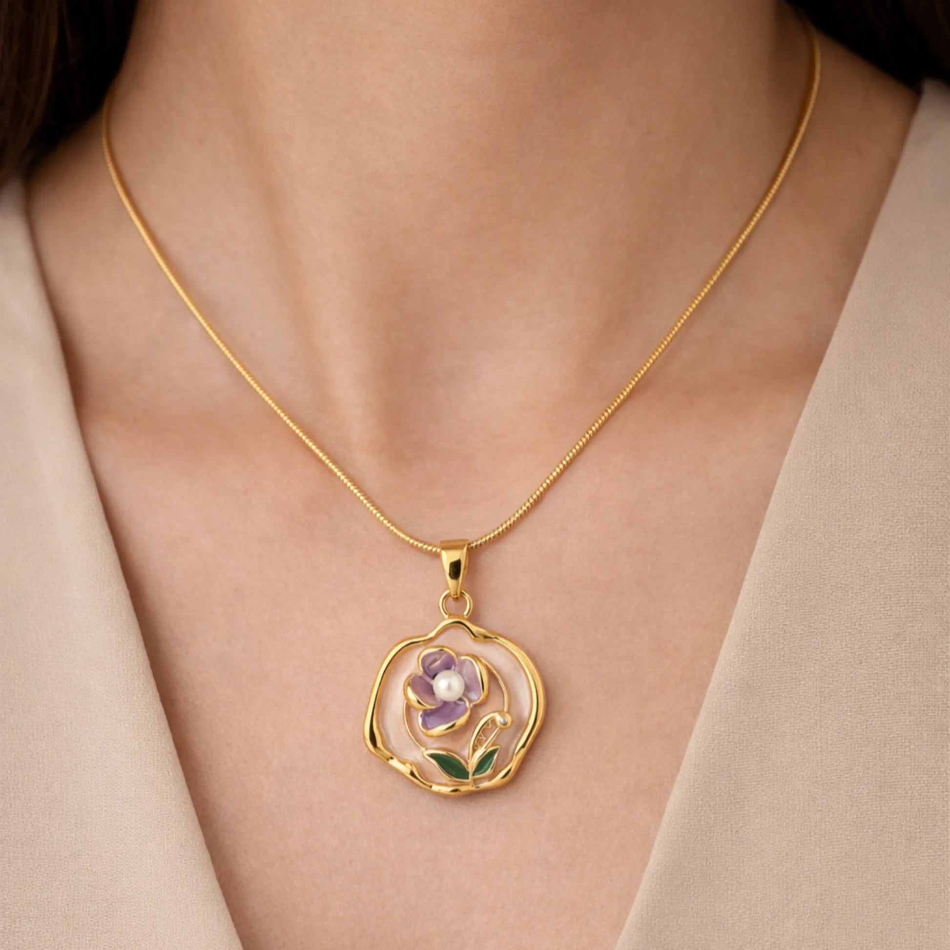 Gold necklace with a floral pendant on a person wearing a beige outfit