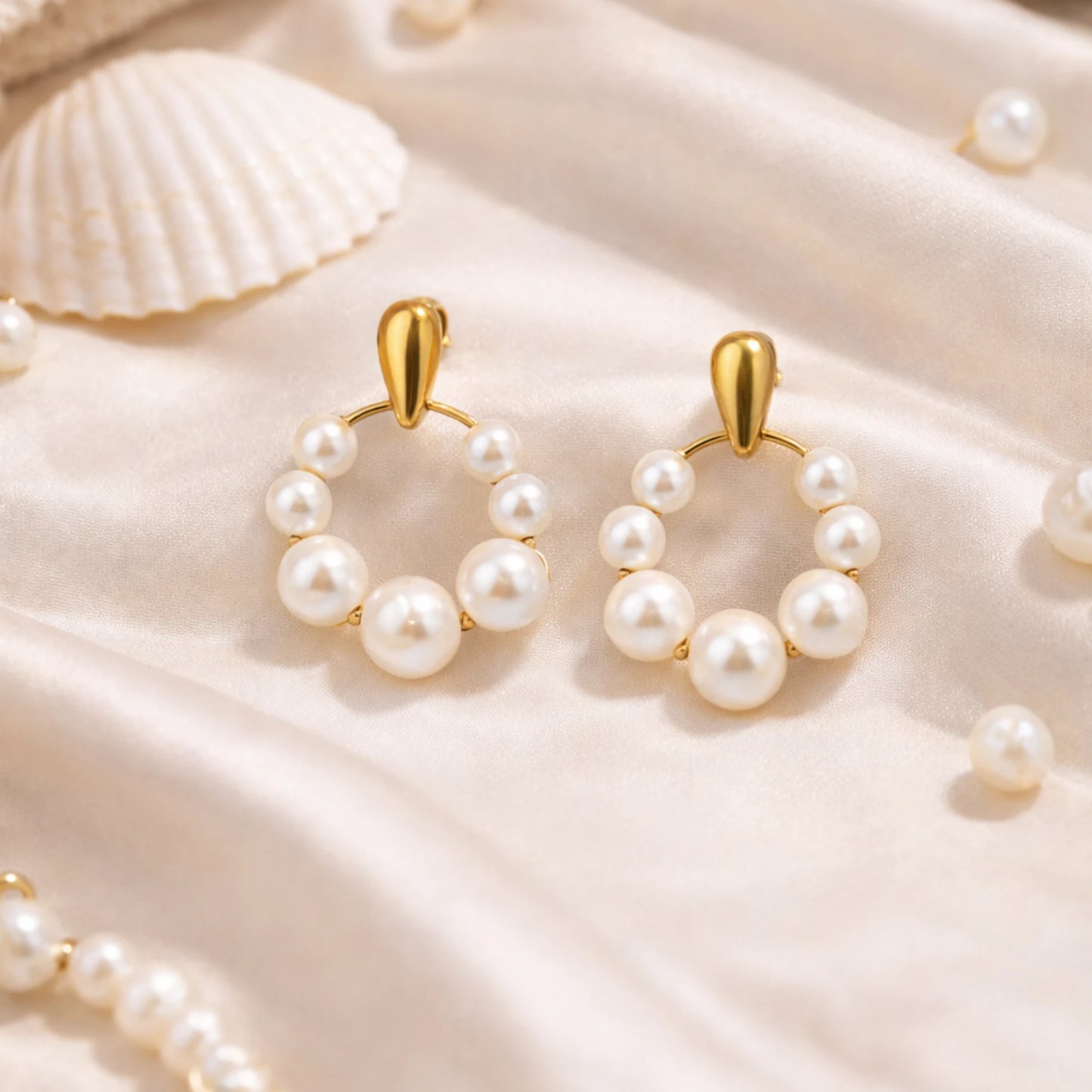 Pearl hoop earrings with gold hooks on a beige fabric background