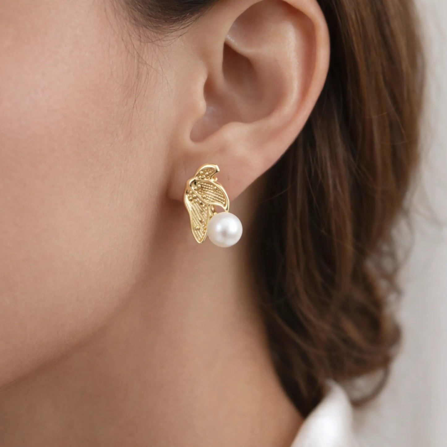 Model wearing YUBIRAA pearl leaf earrings in side angle view showcasing elegant gold leaf design and pearl drop on ear