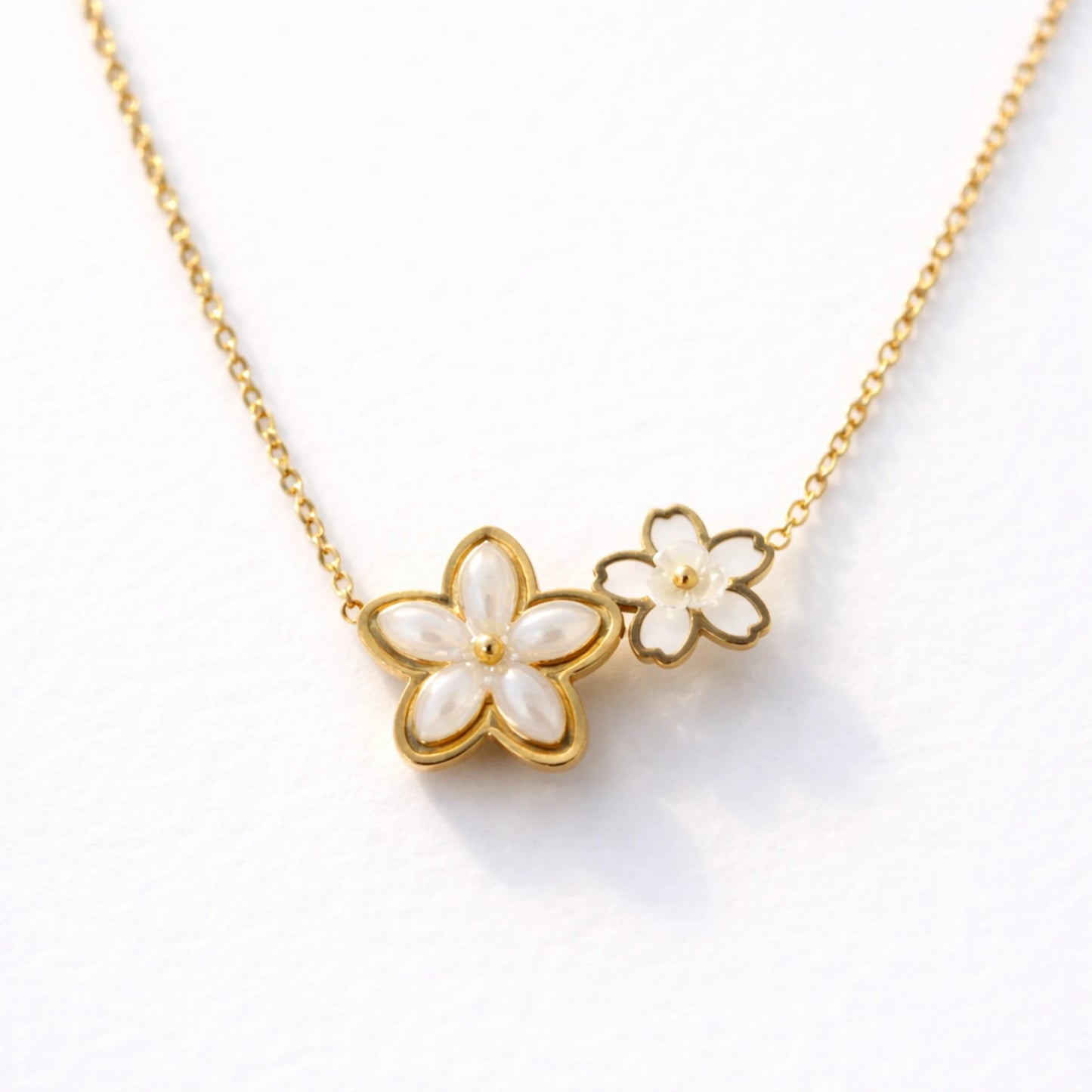 Gold necklace with white floral pendants on a white background