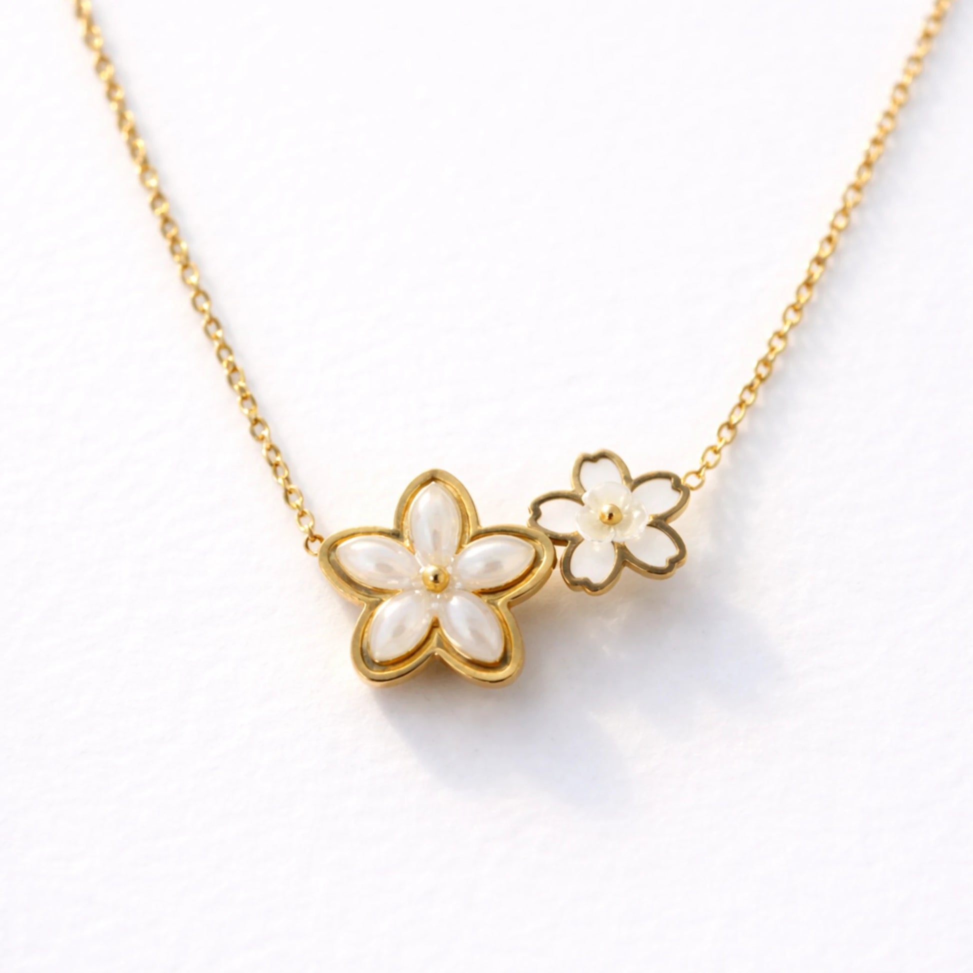 Gold necklace with white floral pendants on a white background