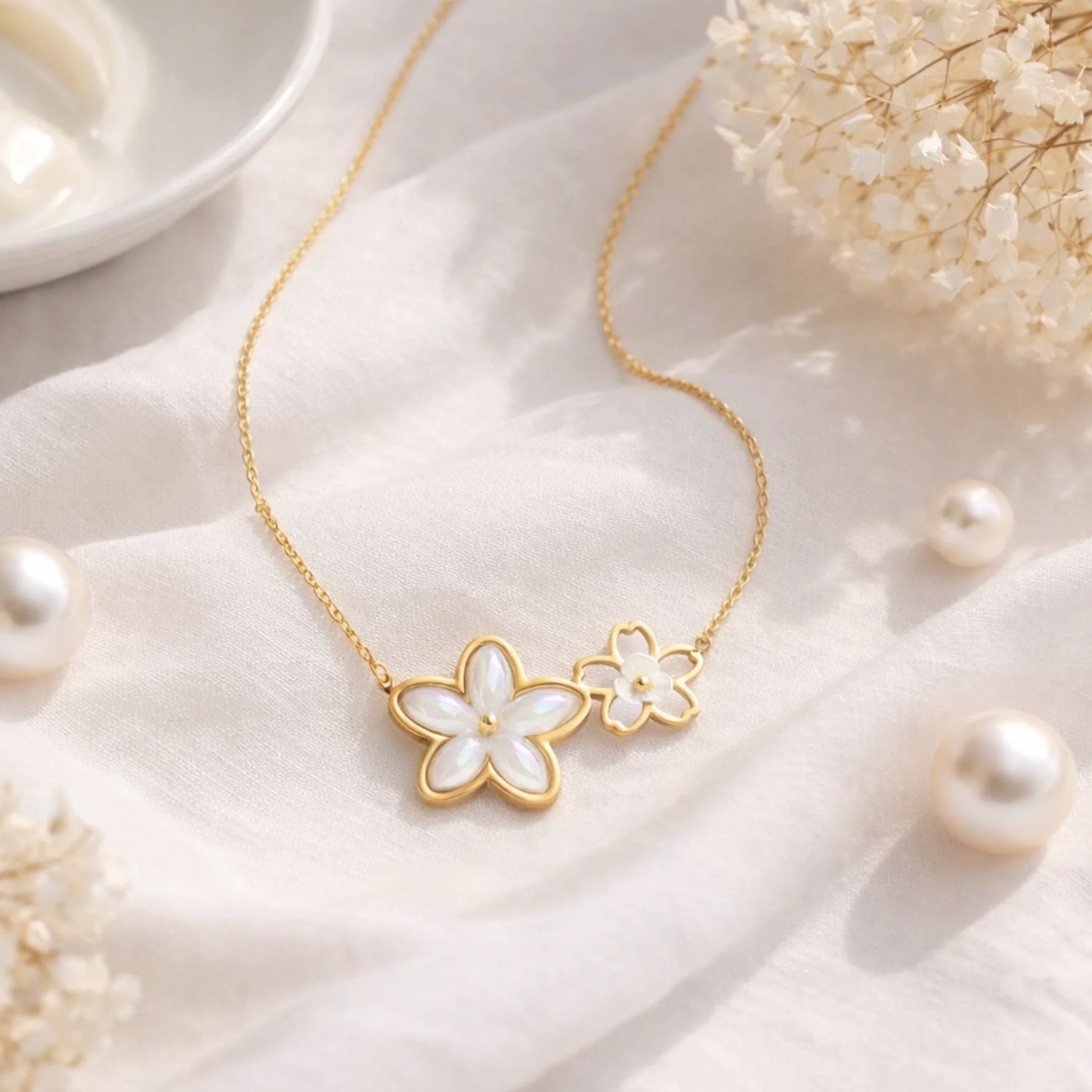 Gold necklace with floral pendants on a soft fabric background