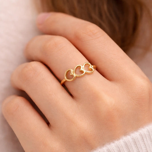 YUBIRAA triple heart gold ring worn on finger, showcasing delicate open-heart design and adjustable fit