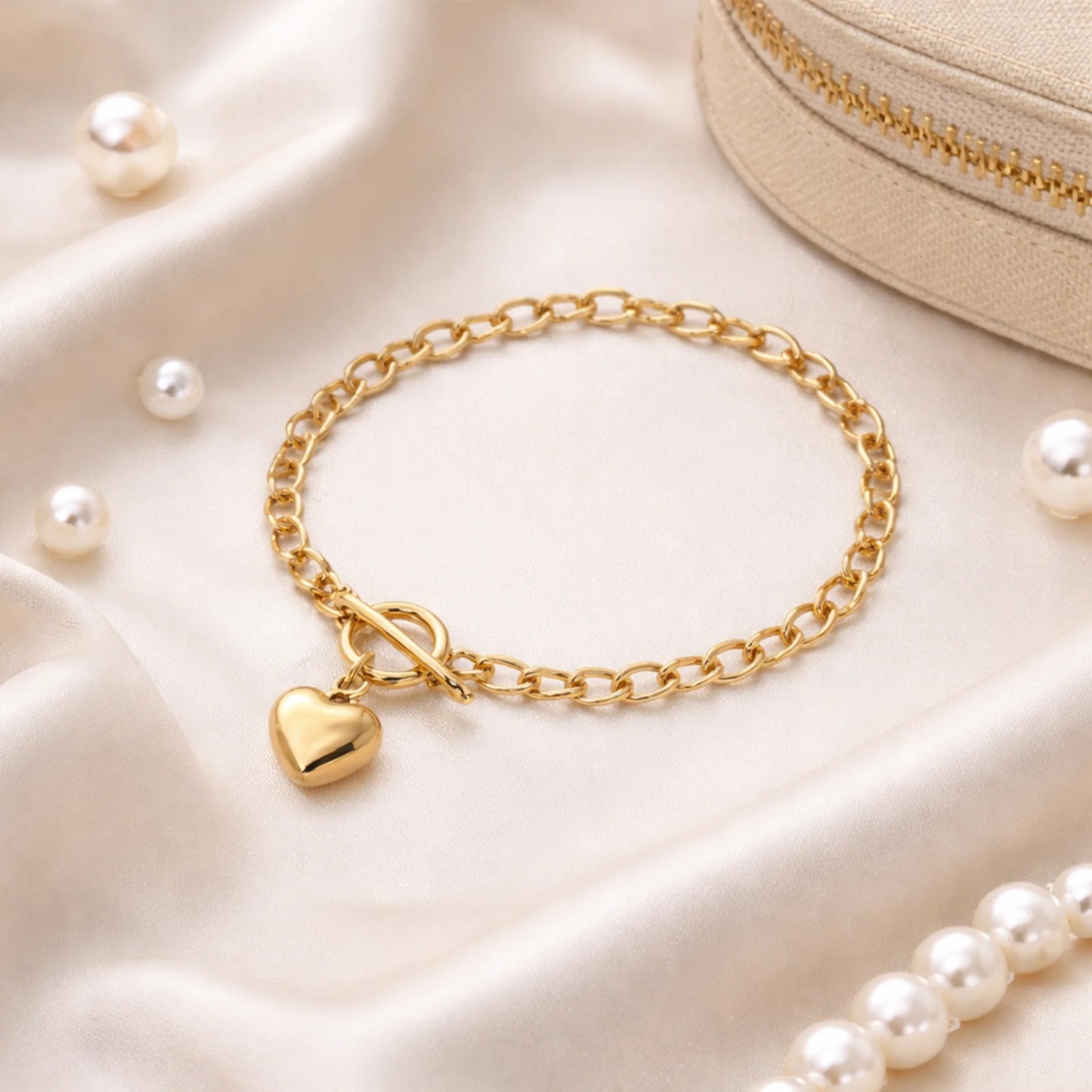 Gold bracelet with a heart charm on a soft beige fabric background