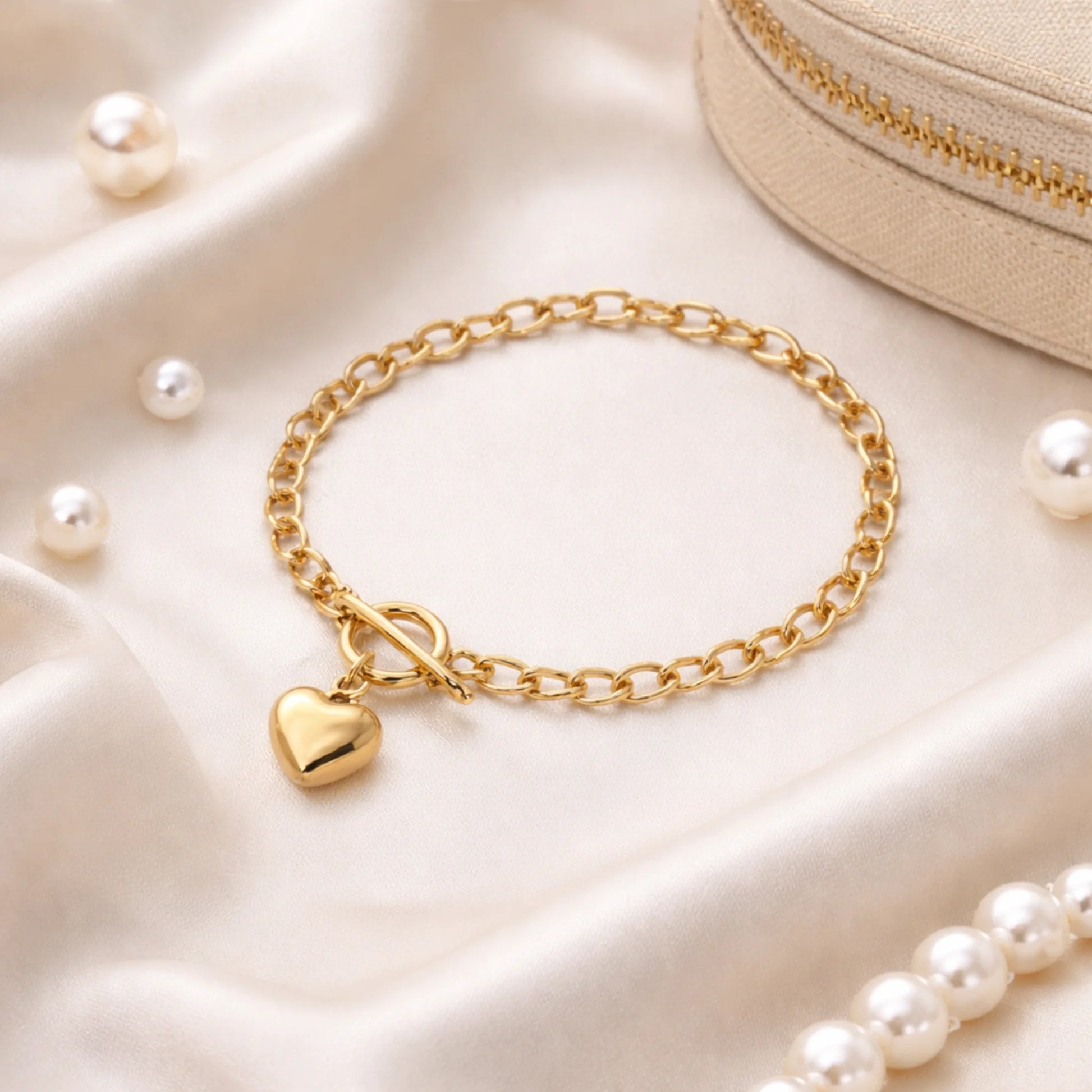 Gold bracelet with a heart charm on a soft beige fabric background