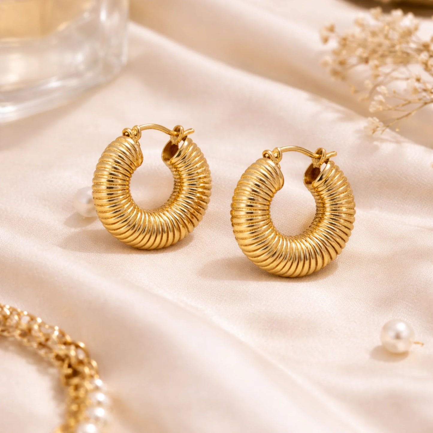 Gold hoop earrings on a soft beige fabric background