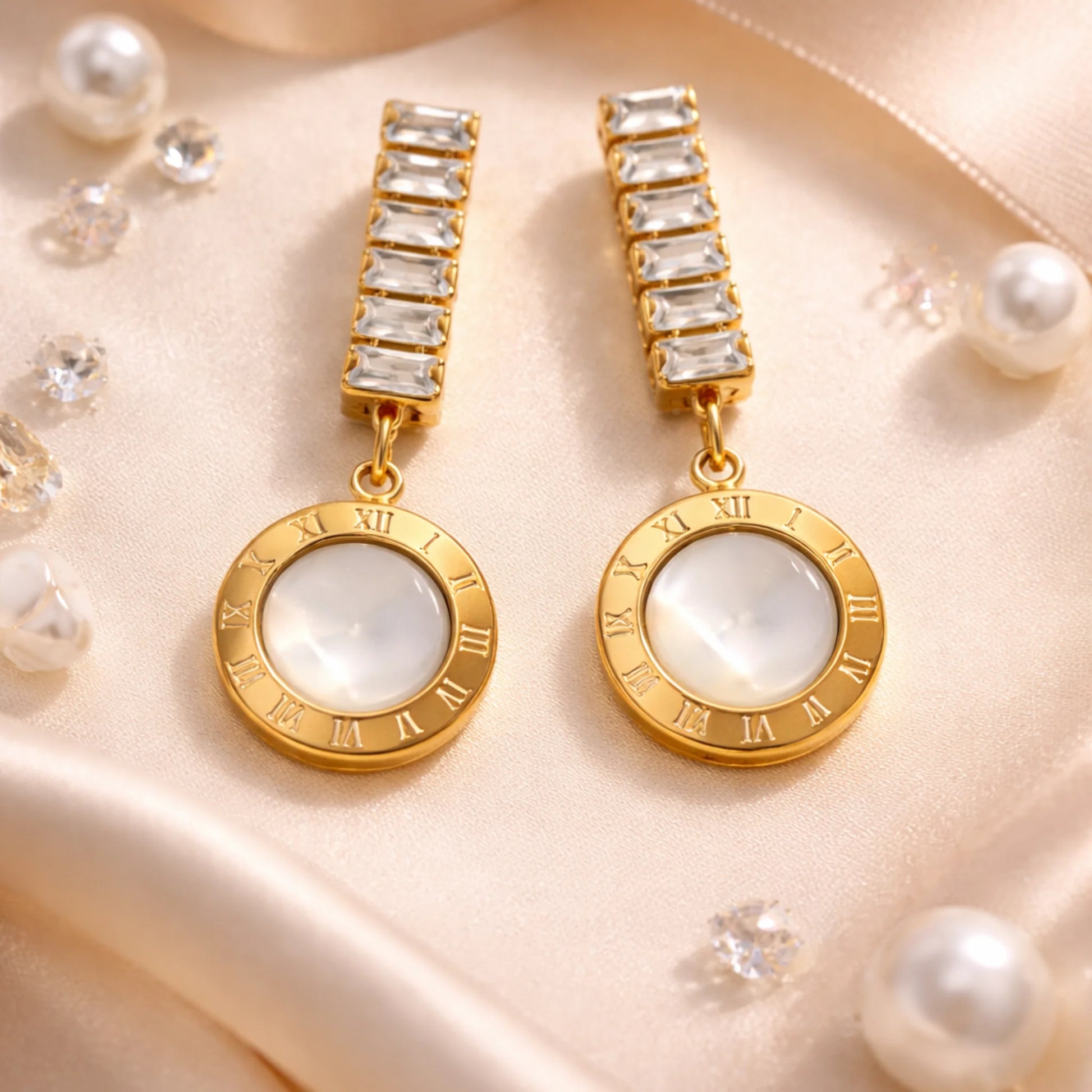 Gold earrings with white gemstones on a beige fabric background