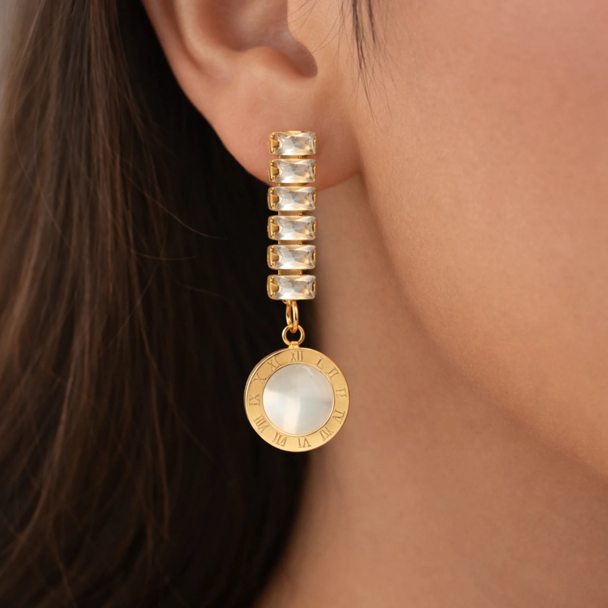 Gold earring with a drop worn by a person