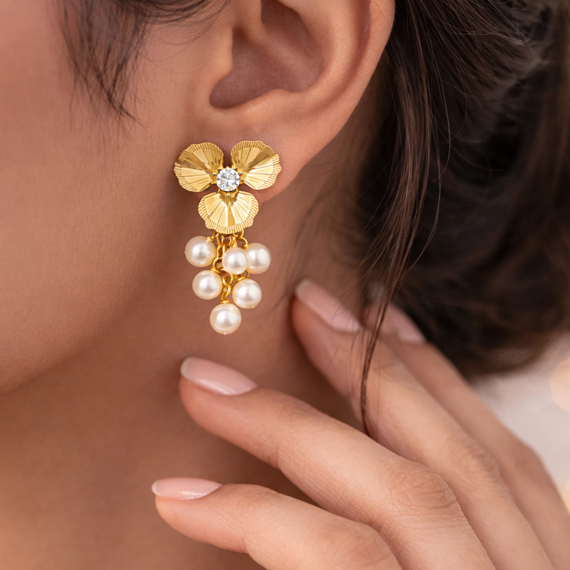 Gold earring with pearls worn by a person