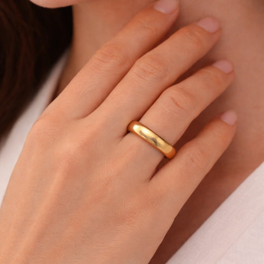 Gold ring on a person's finger with a neutral background
