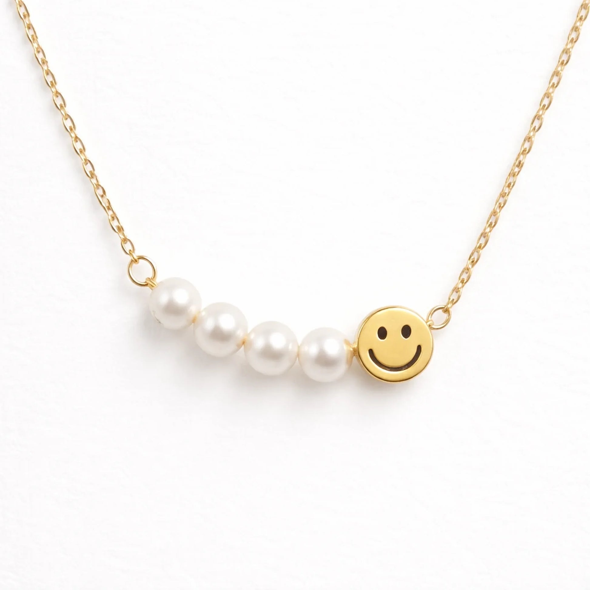 Necklace with pearl beads and a smiley face charm on a white background