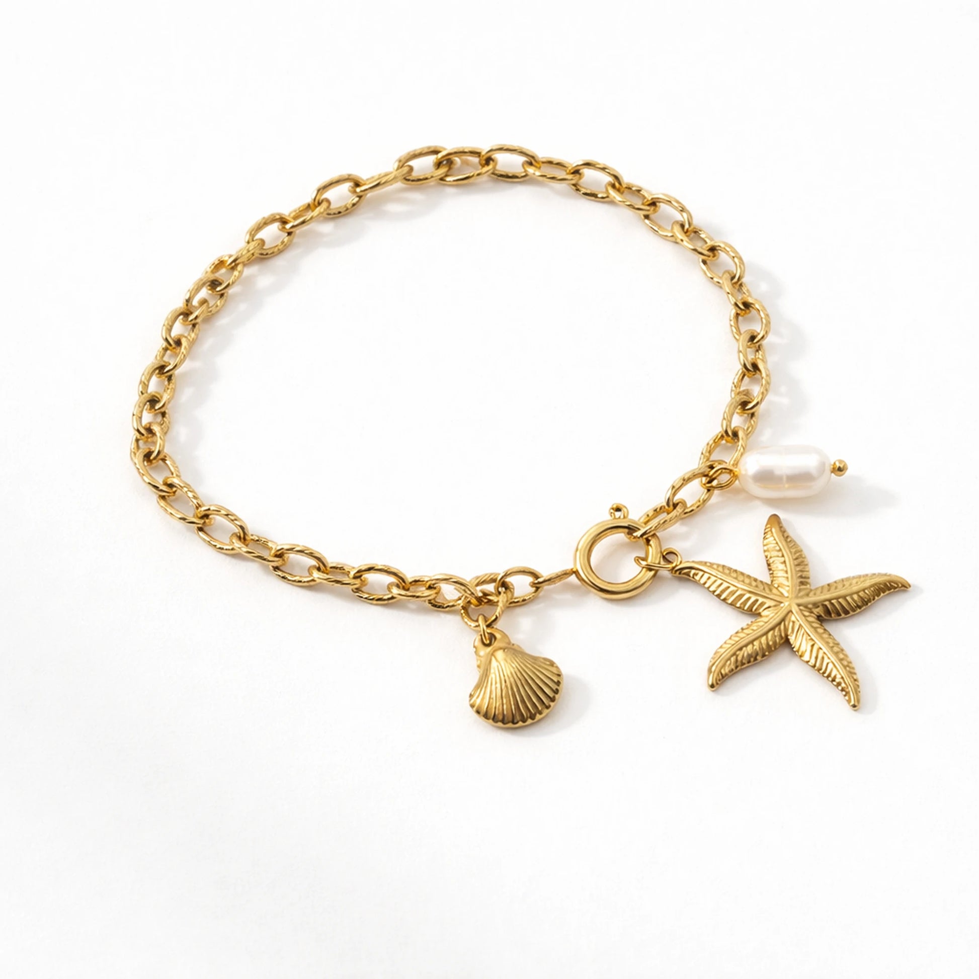 Gold bracelet with starfish and shell charms on a white background