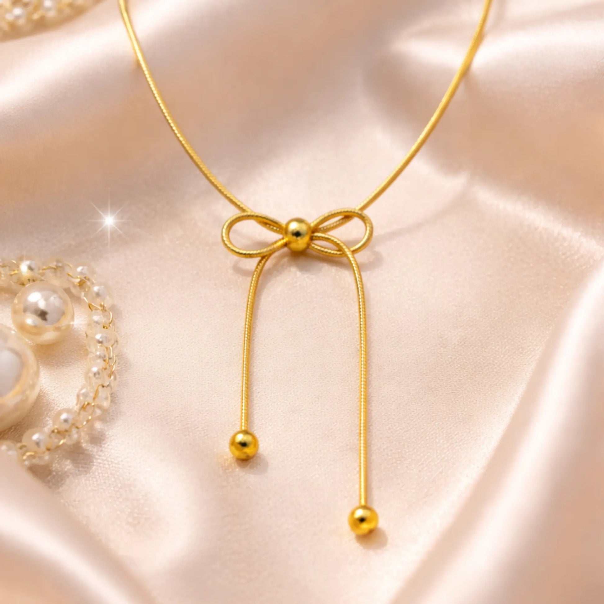 Yubiraa Bow Slider Necklace styled on satin fabric with soft luxury aesthetic