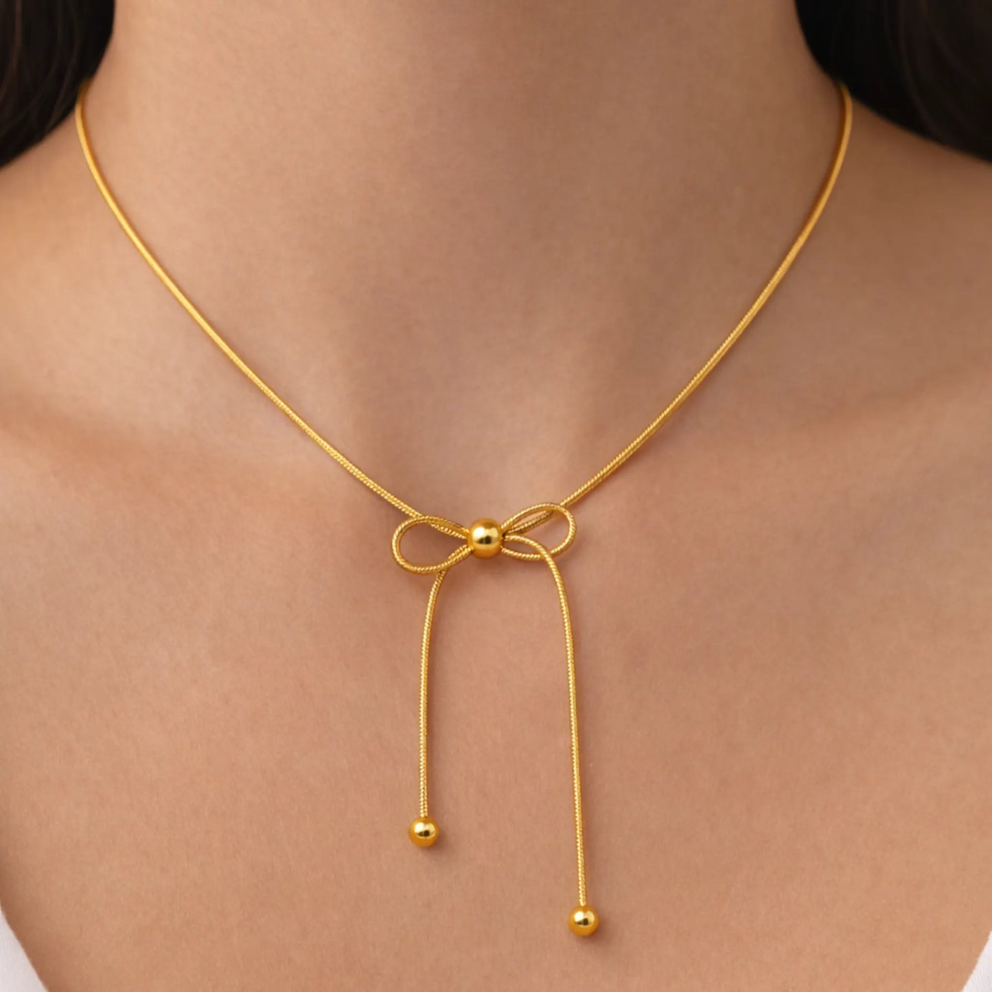 Gold necklace with a bow design on a person's neck