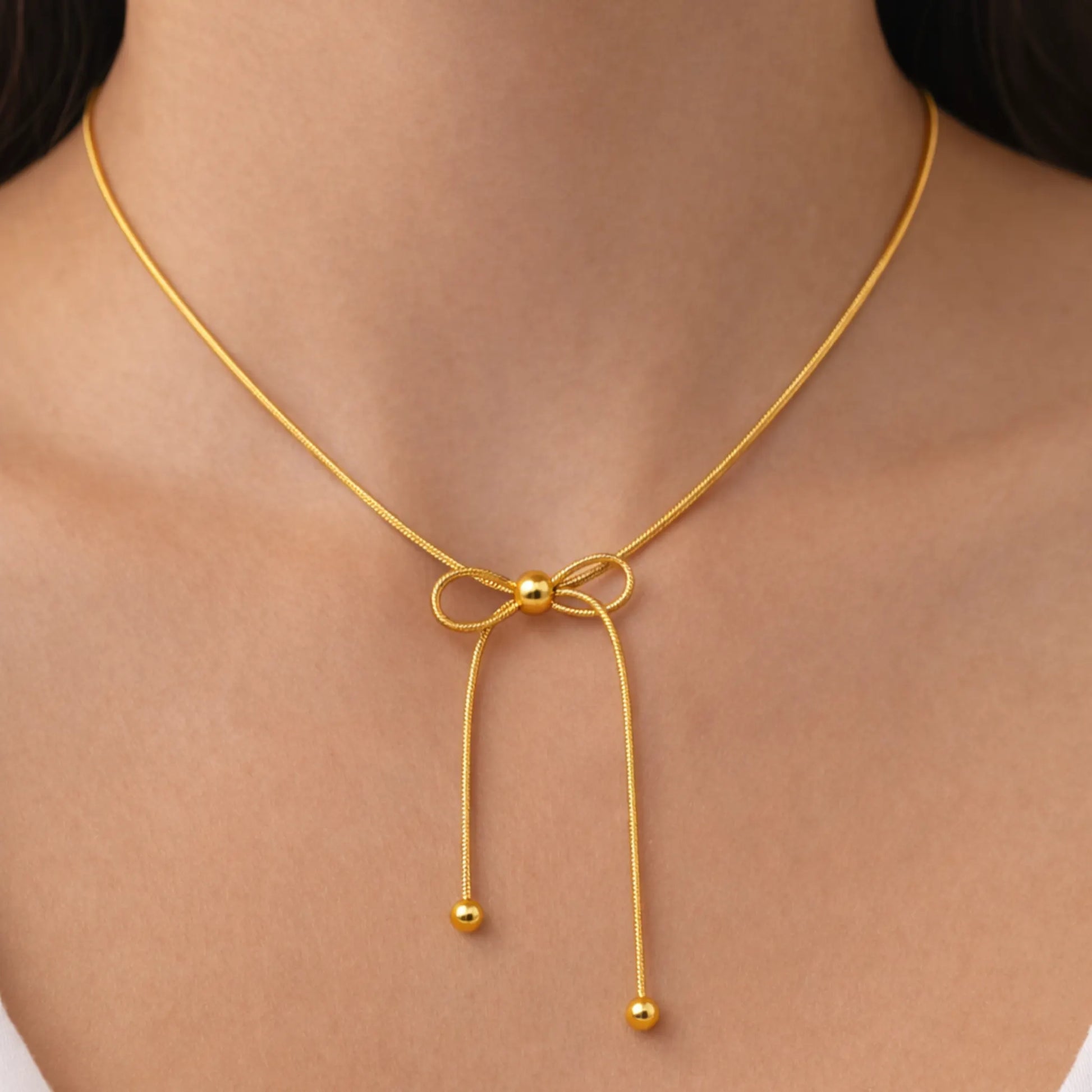 Gold necklace with a bow design on a person's neck
