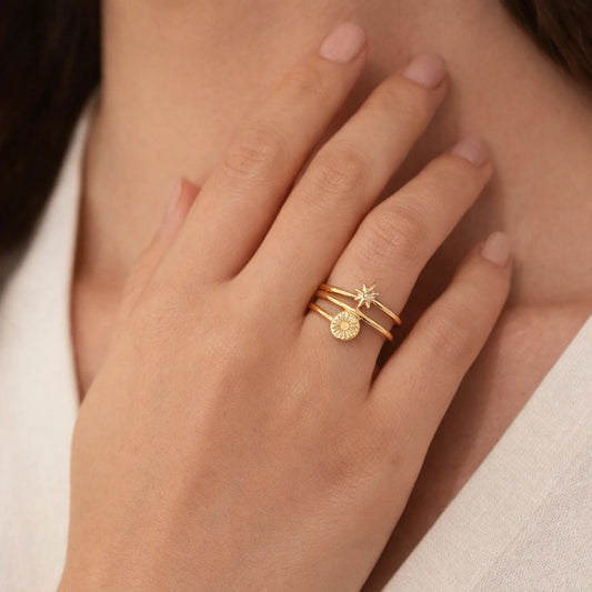 Close-up of a hand wearing two gold rings with star and moon designs.