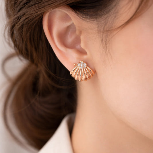 Close-up of a person wearing a rose gold earring with a blurred background