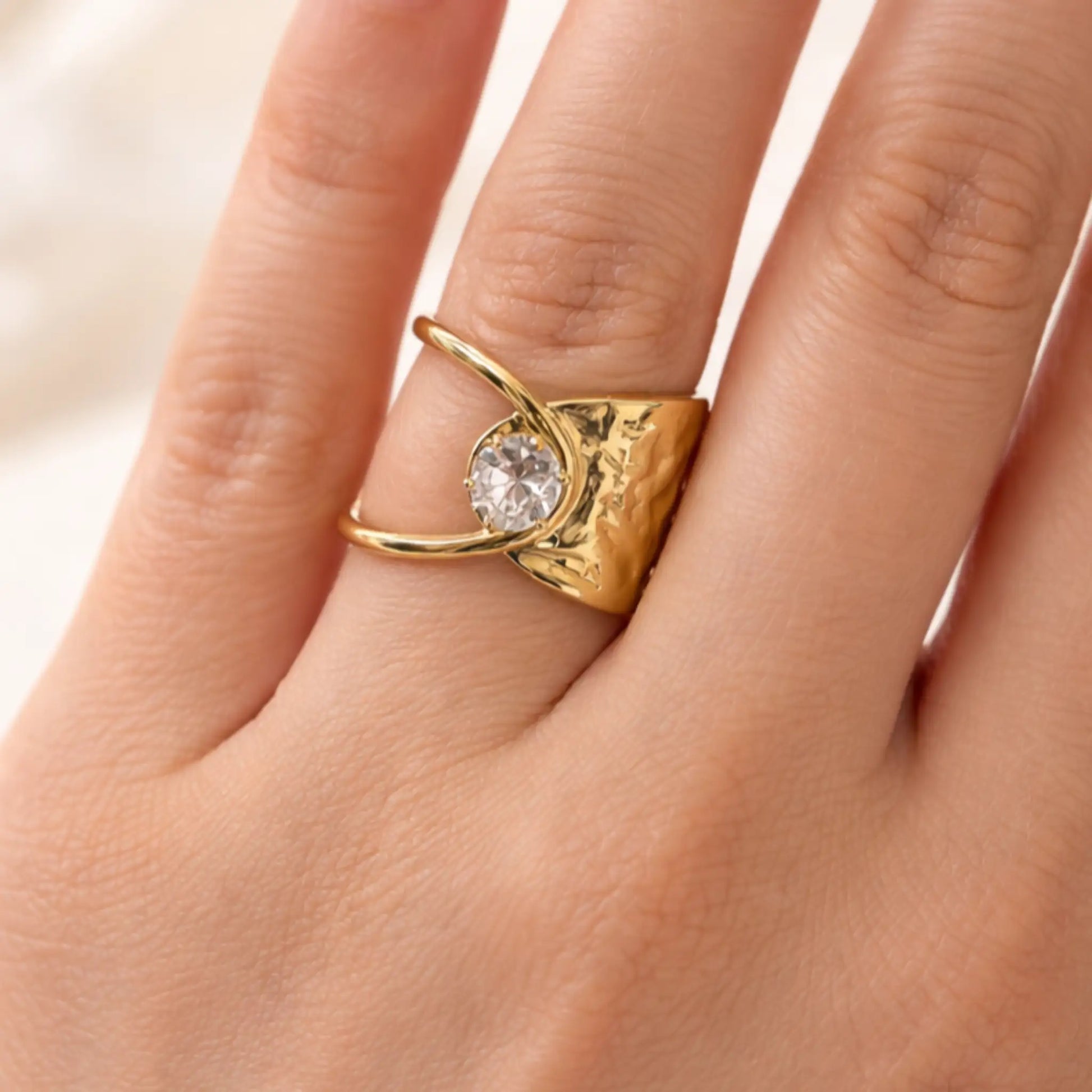 YUBIRAA adjustable gold solitaire ring worn on finger, showcasing modern statement design and crystal accent