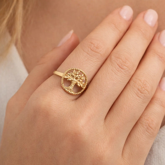 Model wearing gold tree of life ring with circular motif and fine detailing