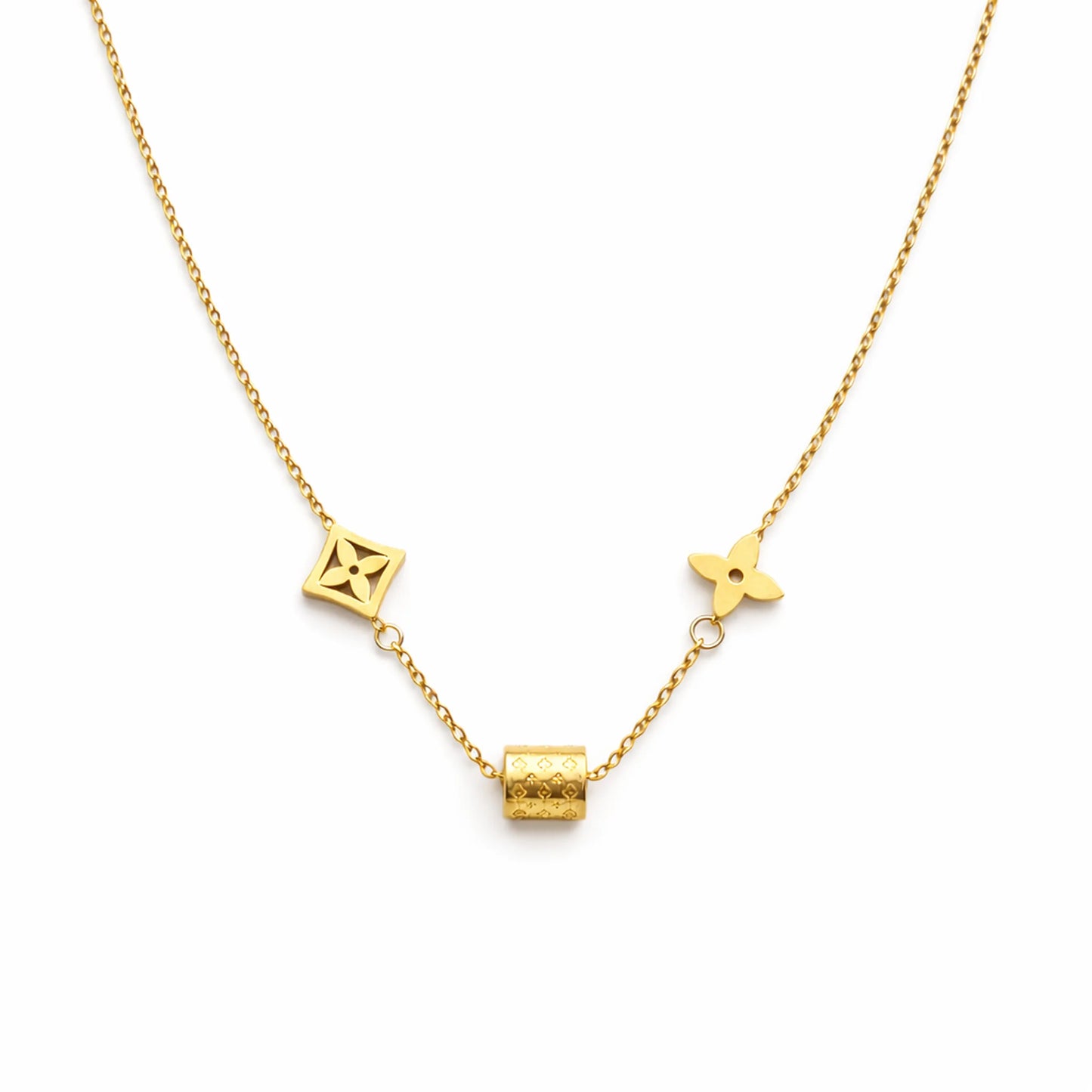 Gold charm necklace with geometric motifs and engraved cylindrical bead on white background