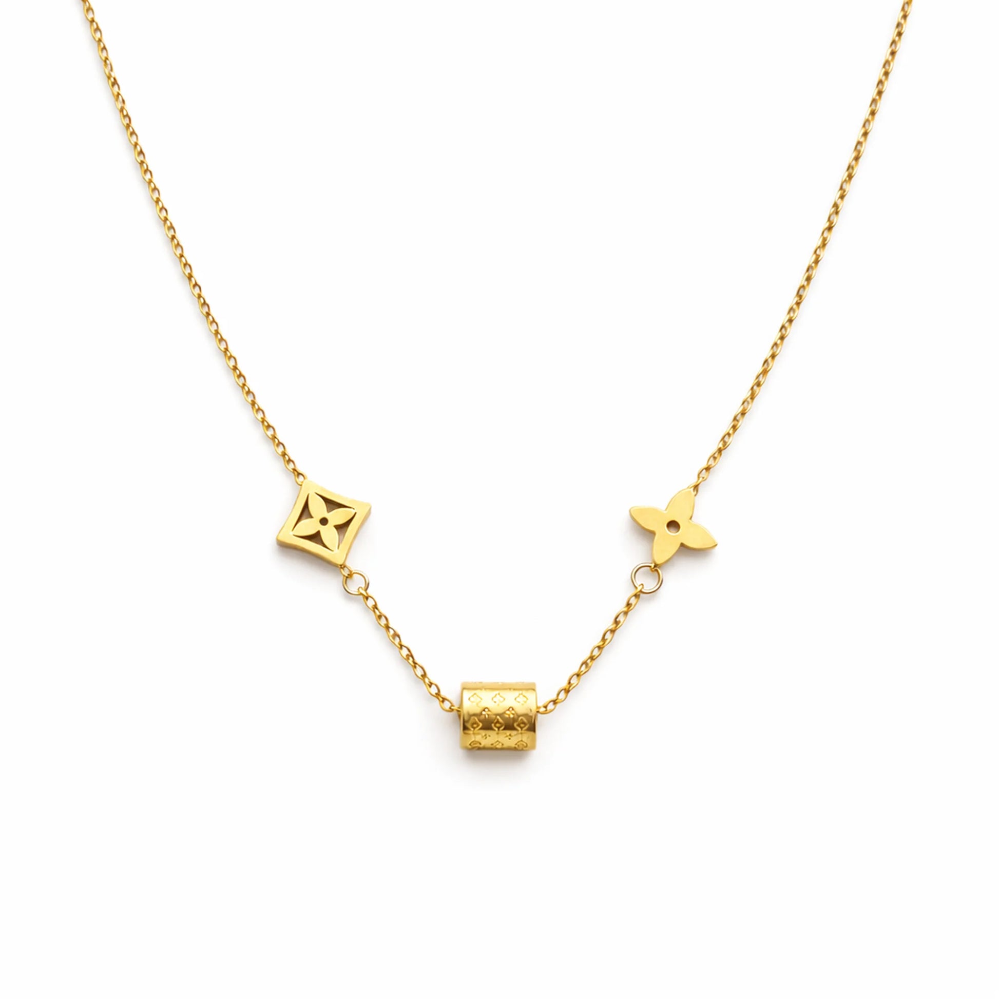 Gold charm necklace with geometric motifs and engraved cylindrical bead on white background