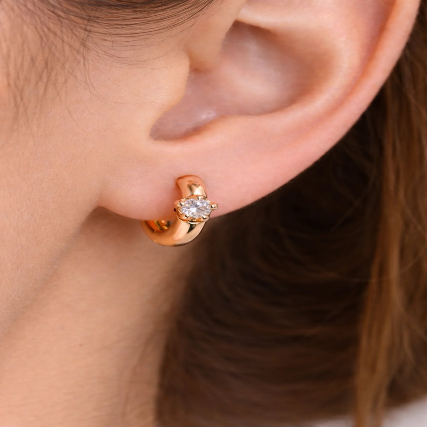 Rose gold hoop earring with a diamond on an ear