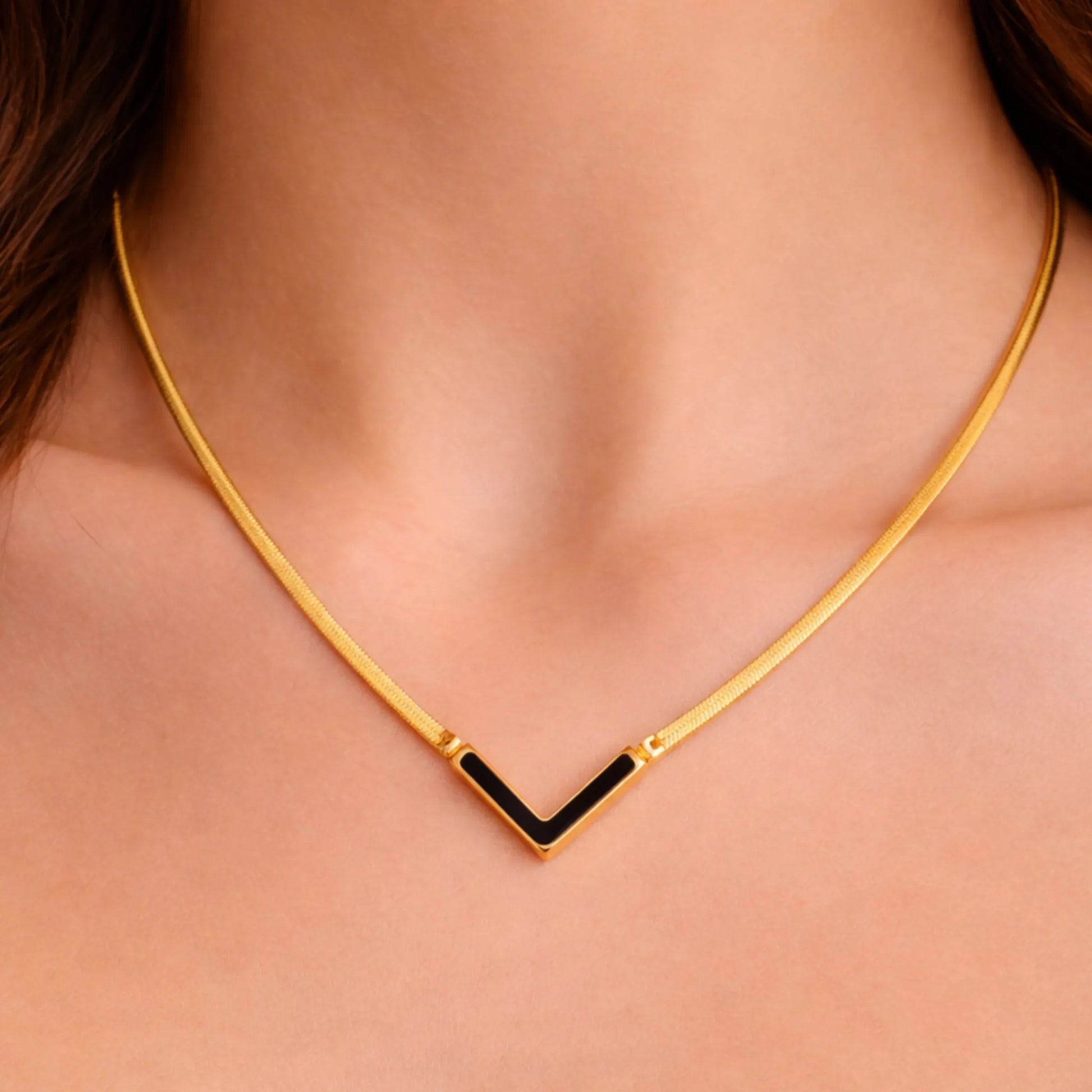 Gold necklace with a black accent worn by a person
