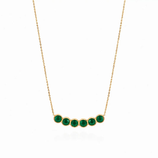 Gold necklace with green gemstones on a white background