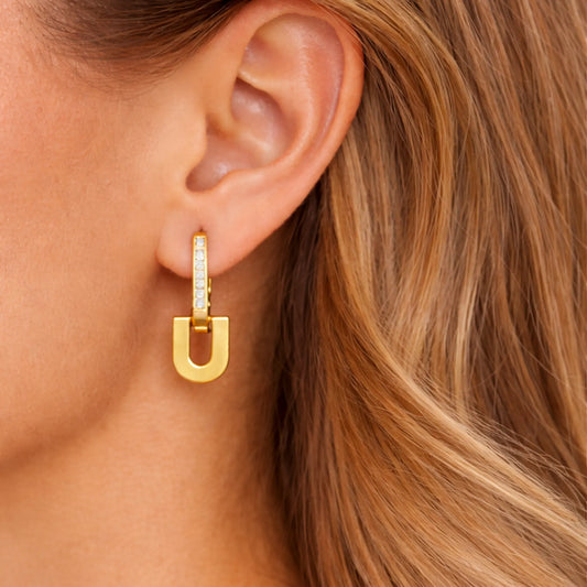 Model wearing YUBIRAA Glowlock gold-plated U-shaped earrings with crystal detailing, side-angle close-up showing elegant fit on ear
