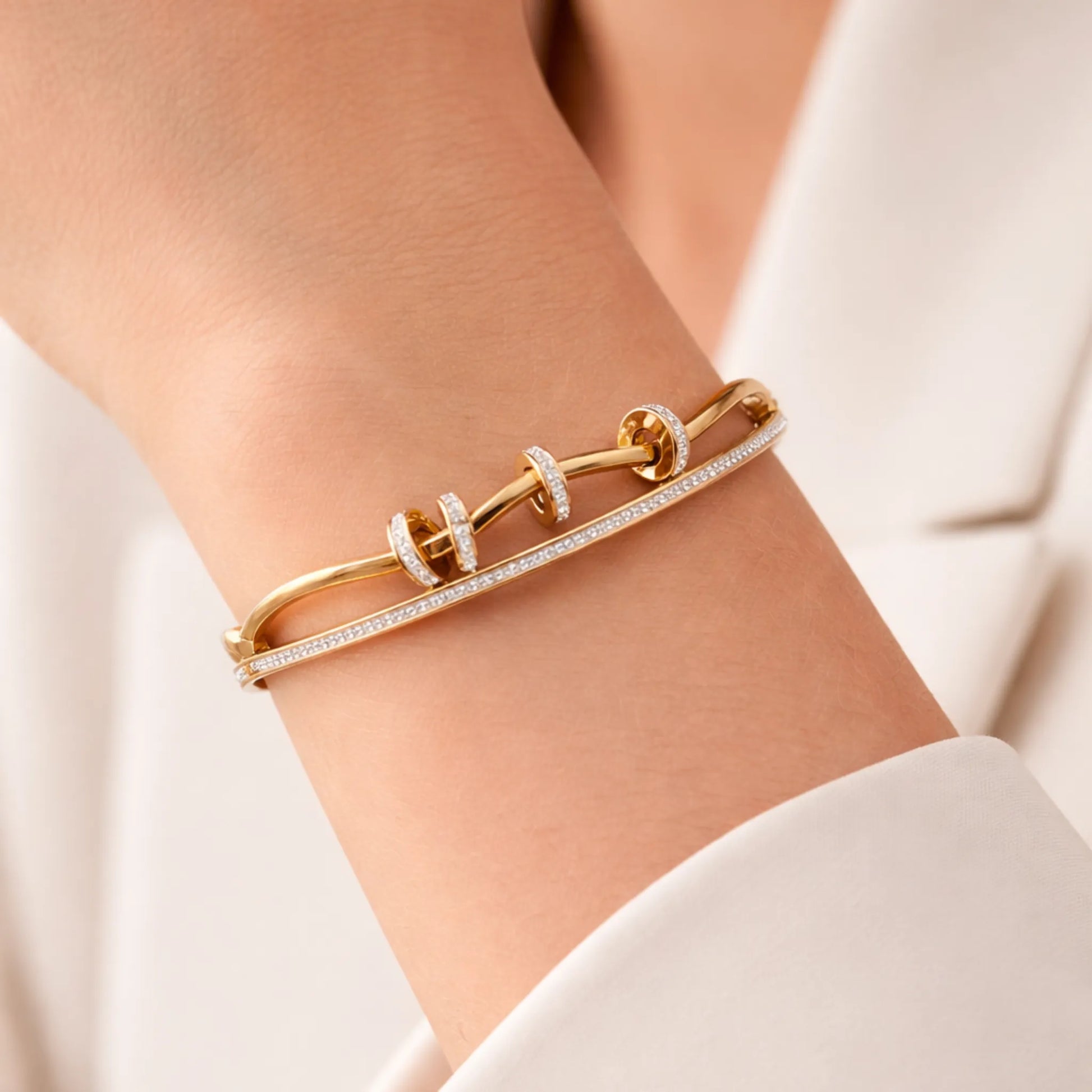 Gold bracelet with diamonds on a person's wrist against a neutral background