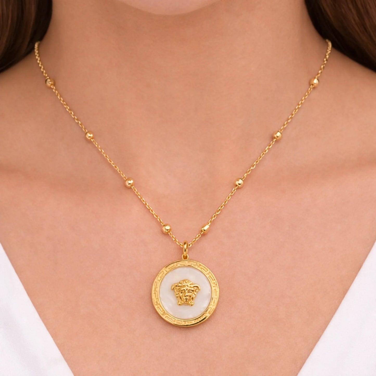 “Model wearing Yubiraa anti tarnish gold plated medallion necklace with ivory stone center and evenly spaced beads, neck-only view”