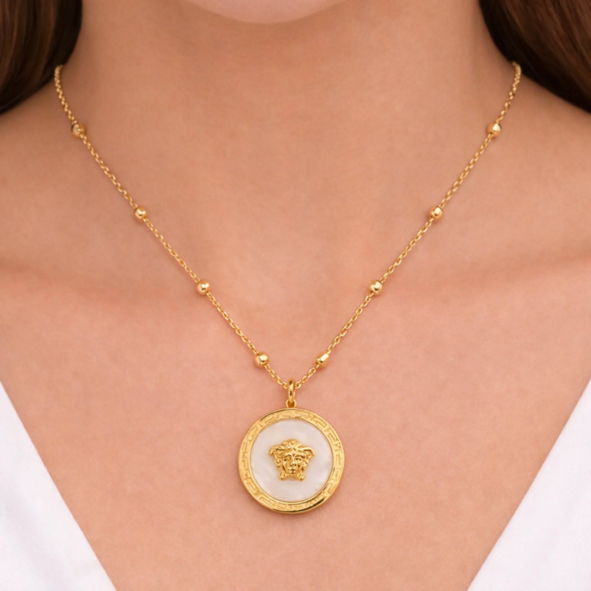 “Model wearing Yubiraa anti tarnish gold plated medallion necklace with ivory stone center and evenly spaced beads, neck-only view”