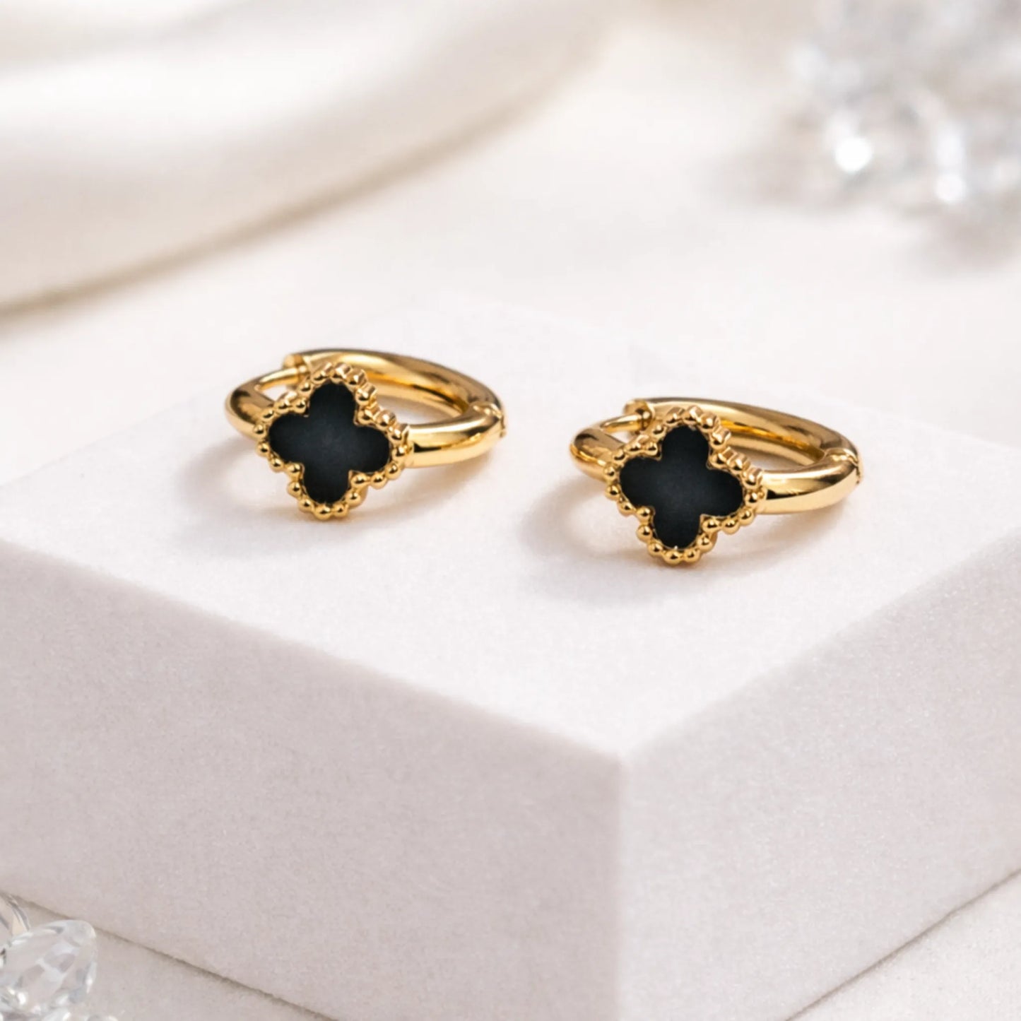 Midnight Bloom hoop earrings by YUBIRAA featuring black clover design with anti tarnish gold polish styled on white base
