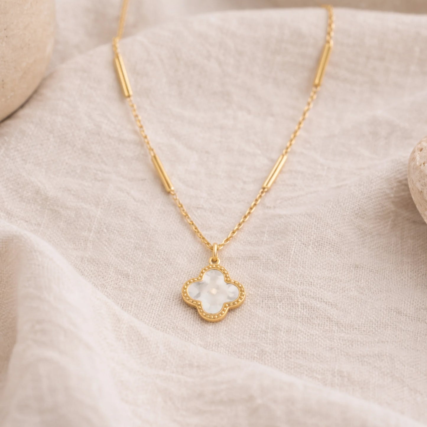 Yubiraa Final Ivory Glow Clover Necklace with ivory clover pendant styled on neutral fabric background