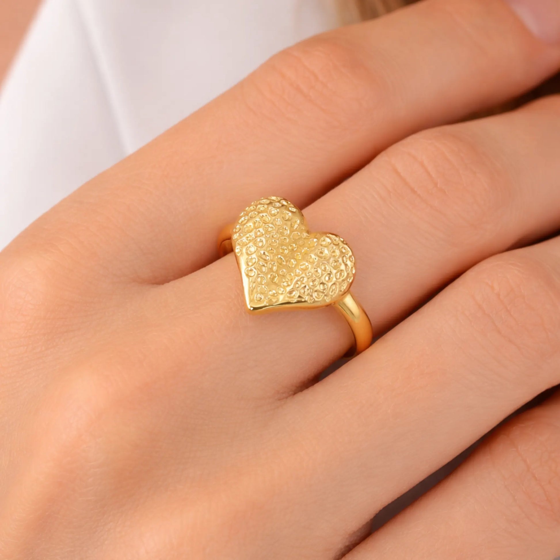 Model wearing gold textured heart adjustable ring on finger